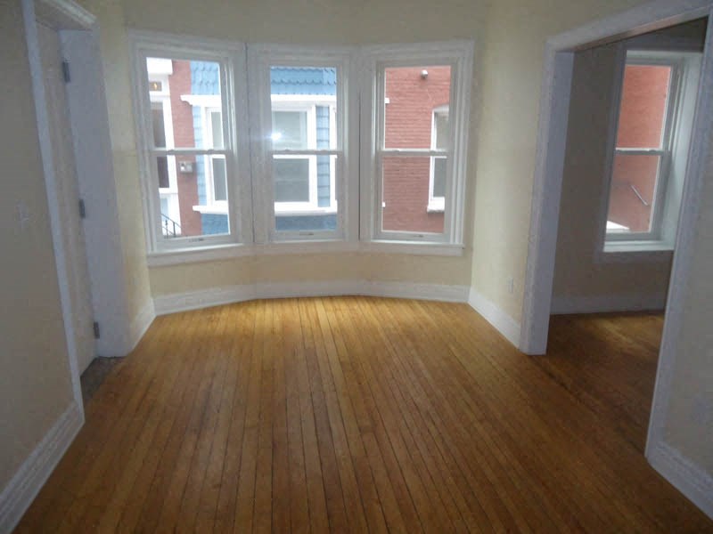 an empty living room with a wood floor and windows