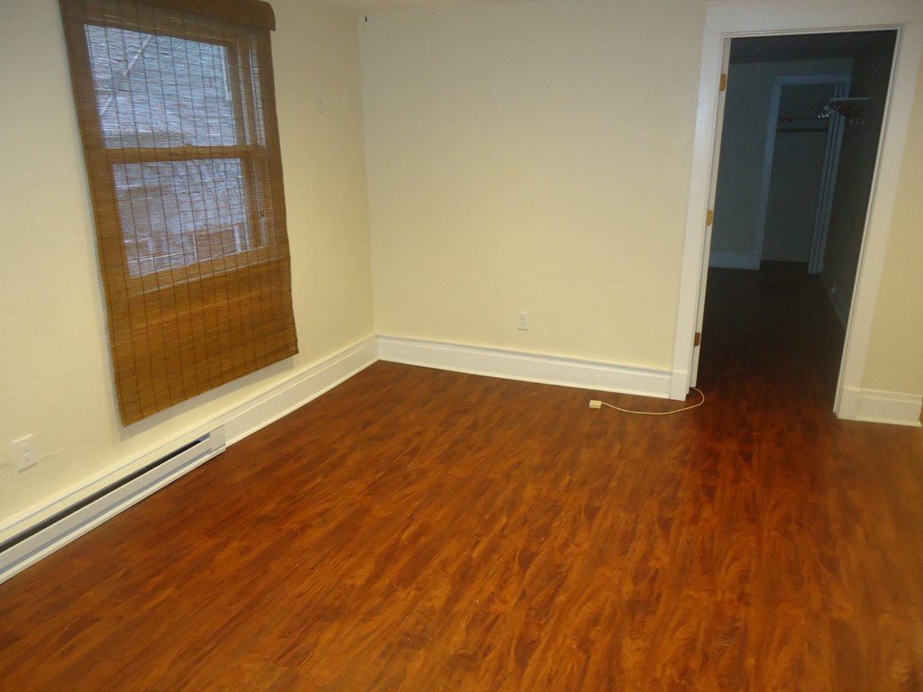 an empty living room with wooden floors and a window