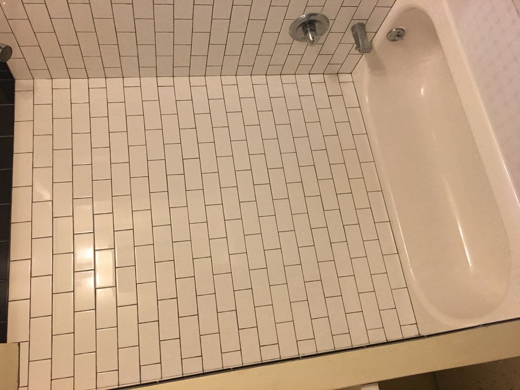 a white tiled bathroom with a tub and a sink