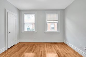 an empty room with two windows and a wooden floor