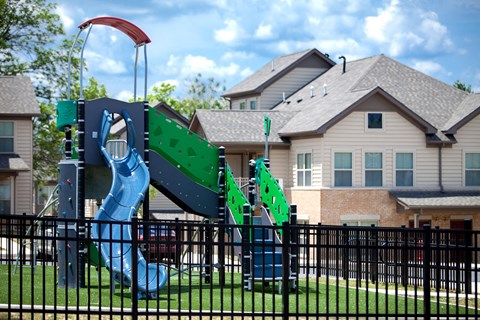 a playground in front of a house with a slide