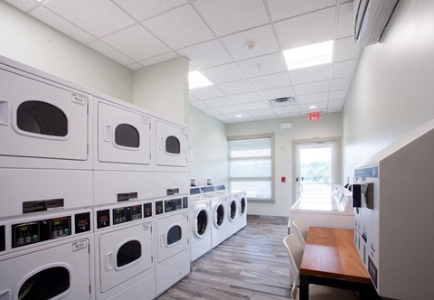 a washer and dryer room with a row of washing machines in a room