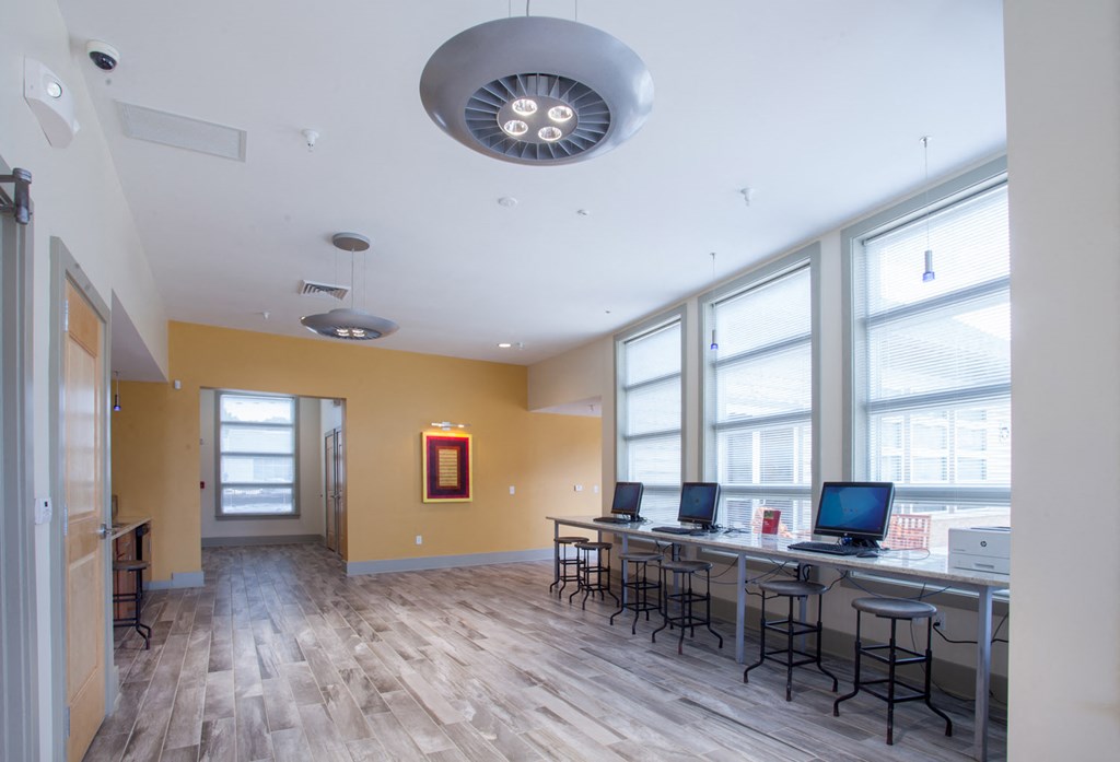 a computer room with desks and chairs and large windows