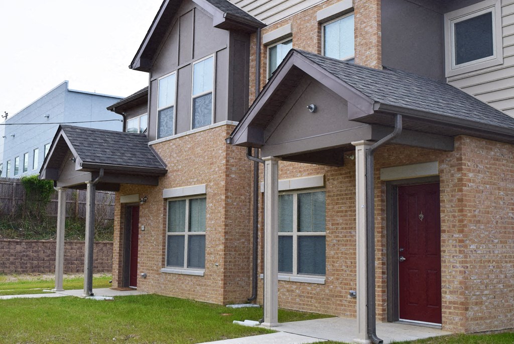 the front of a brick house with a red door
