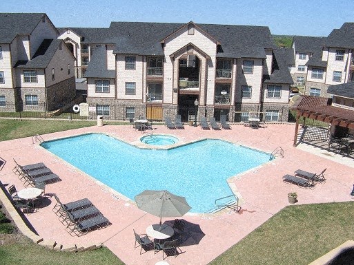 an aerial view of an apartment pool with chairs and umbrellas