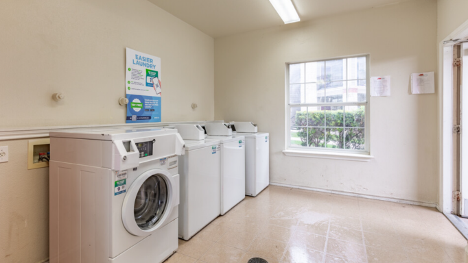 an empty laundry room with washing machines and a window