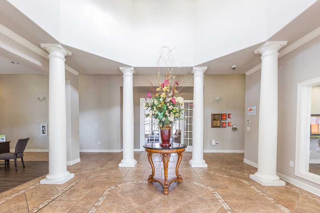 a lobby with columns and a table with a vase of flowers