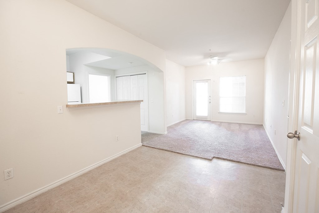an empty living room and kitchen with white walls and tile floors