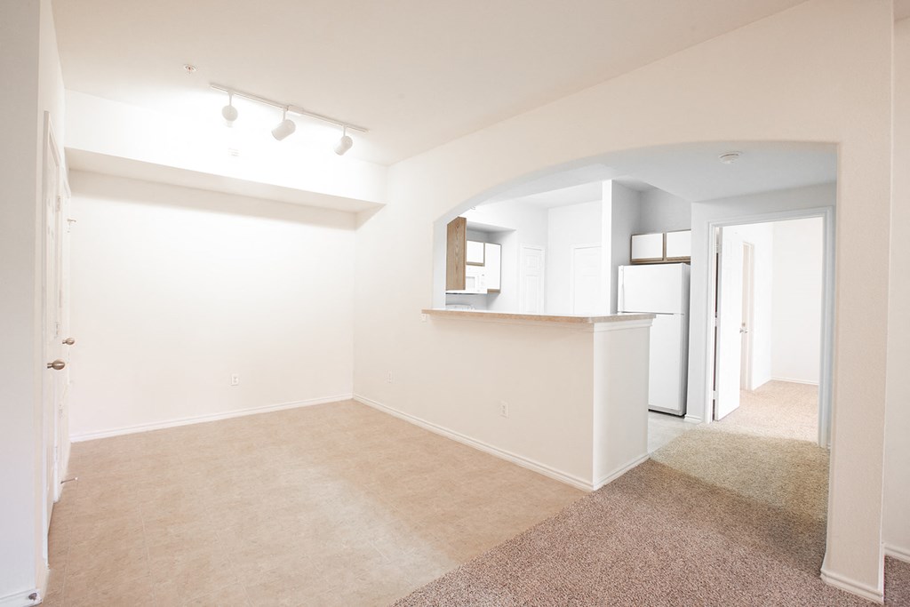 an empty room with a kitchen and a living room