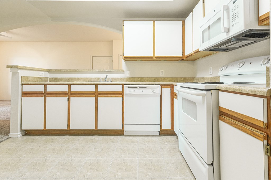 an empty kitchen with white appliances and white cabinets