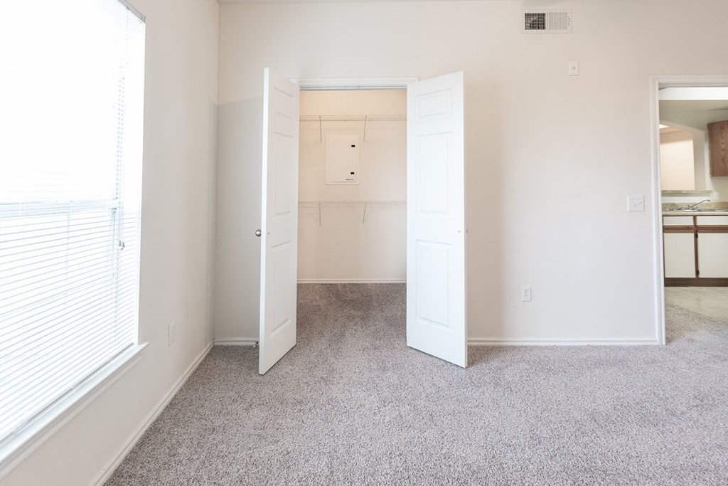 an empty bedroom with a closet and a window