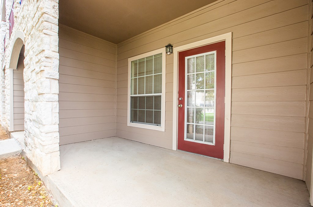the front porch of a home with a red door