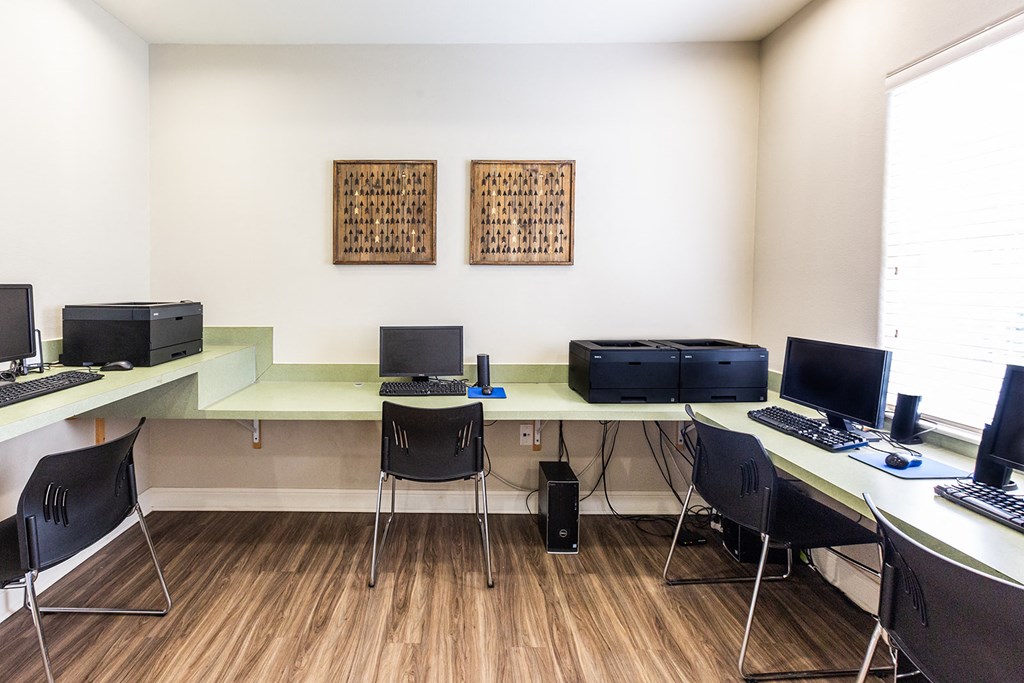a computer room with three desks with computers and monitors