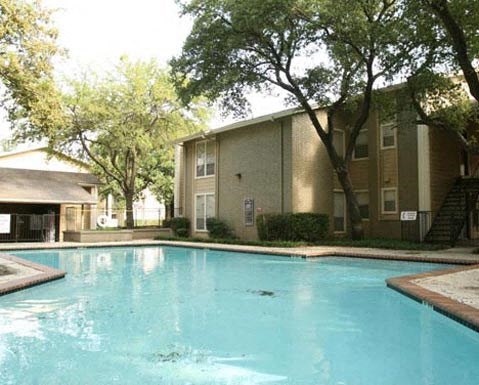 A swimming pool in front of a building surrounded by trees.