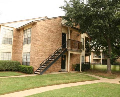 A brick house with a black staircase leading to the front door.