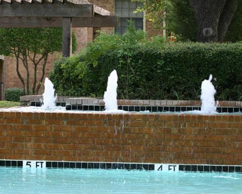 A pool with a fountain in the middle of it.