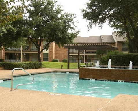 A pool with a slide and a fountain in front of a building.
