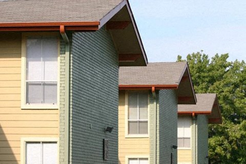 A building with a yellow and green exterior and a brown roof.
