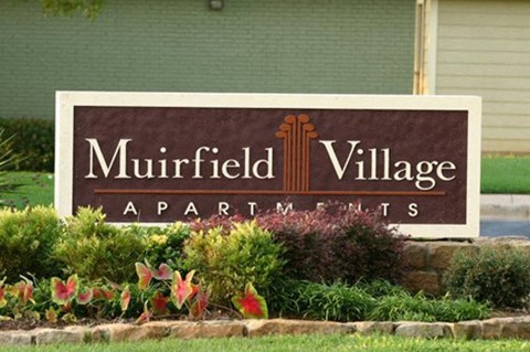 A brown sign that says Muirfield Village Apartments.