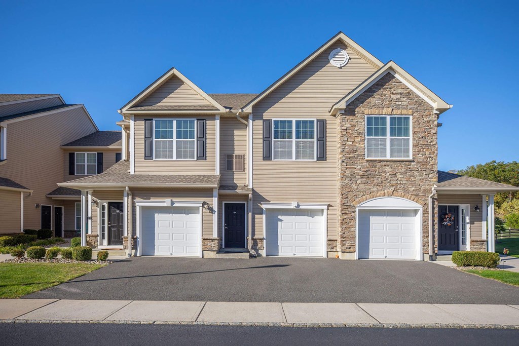 a tan house with white doors and a driveway