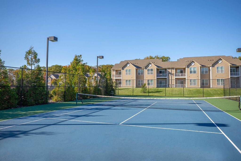 a tennis court with apartments in the background