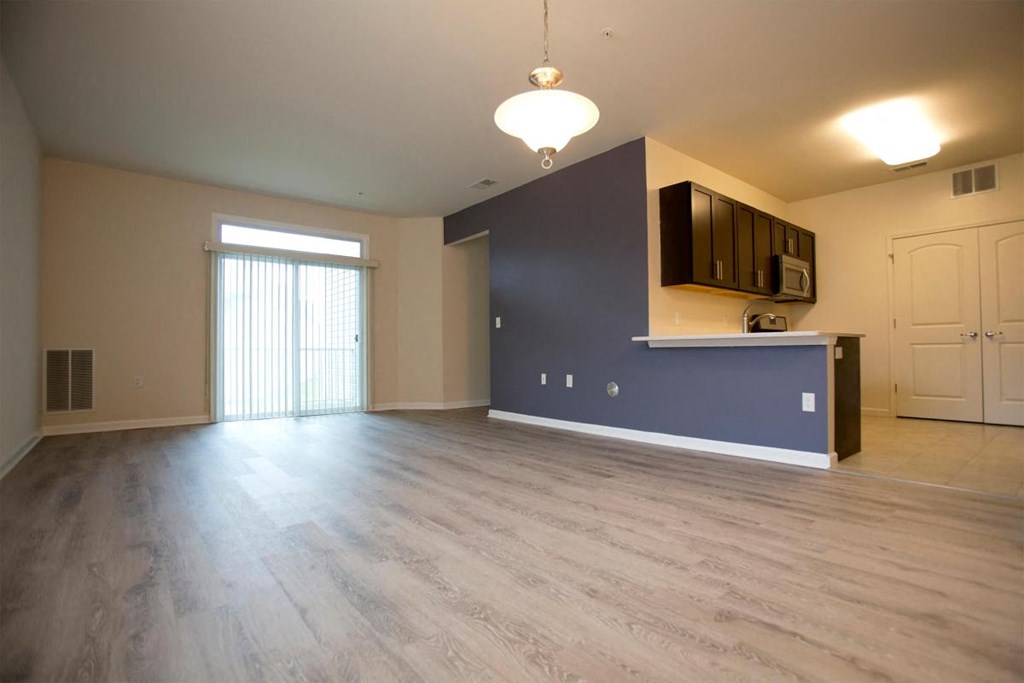an empty living room with a blue accent wall and wood floors