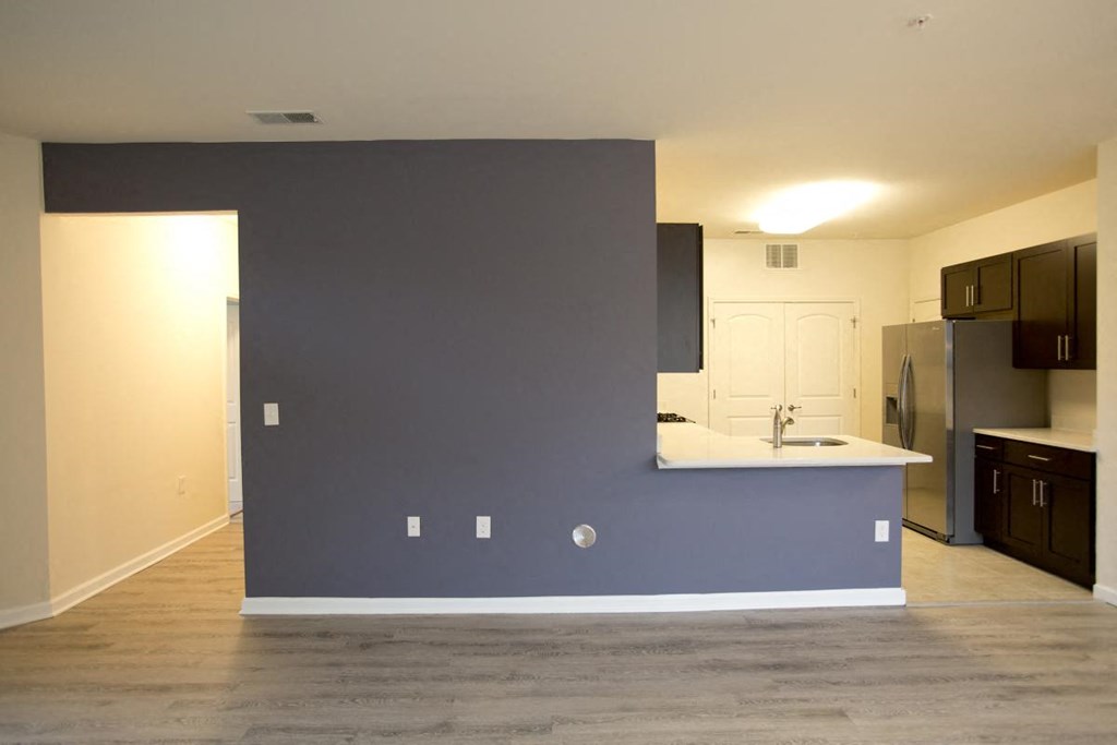 an empty kitchen with a blue accent wall and a stainless steel refrigerator