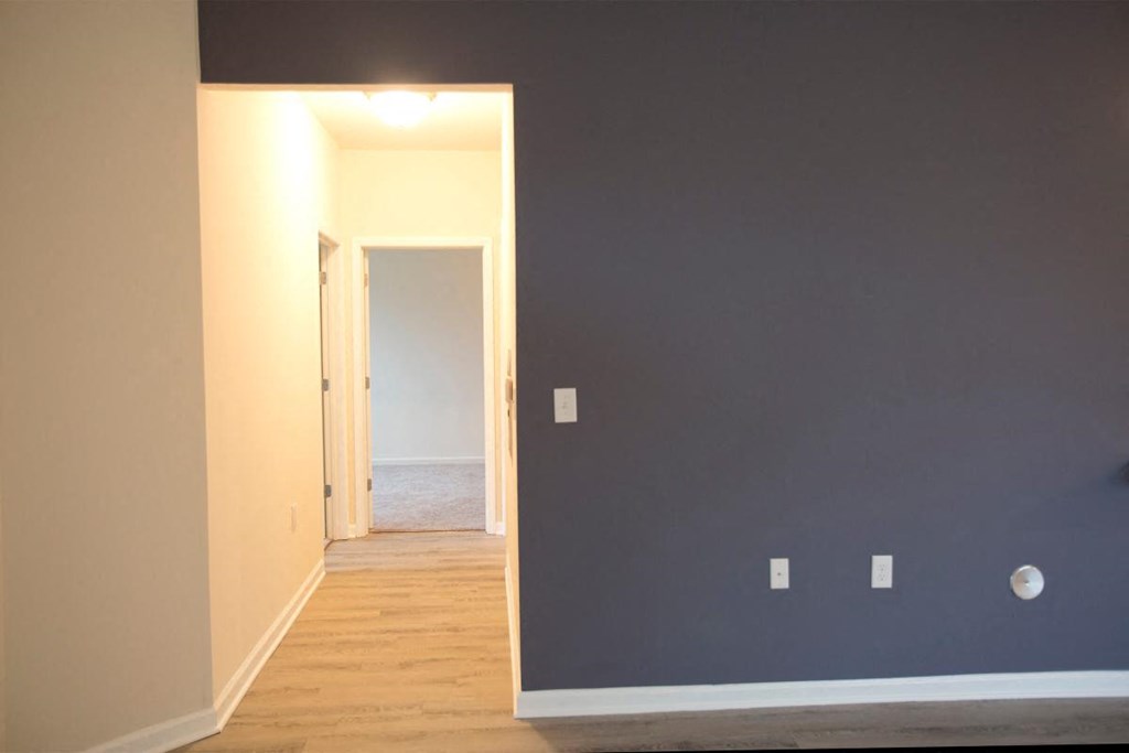 a hallway with a blue wall and a door to a room