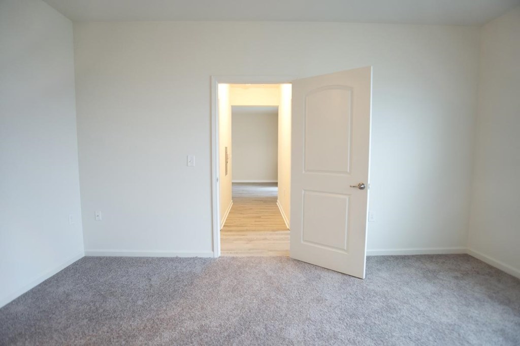 a bedroom with a white door and a carpeted floor