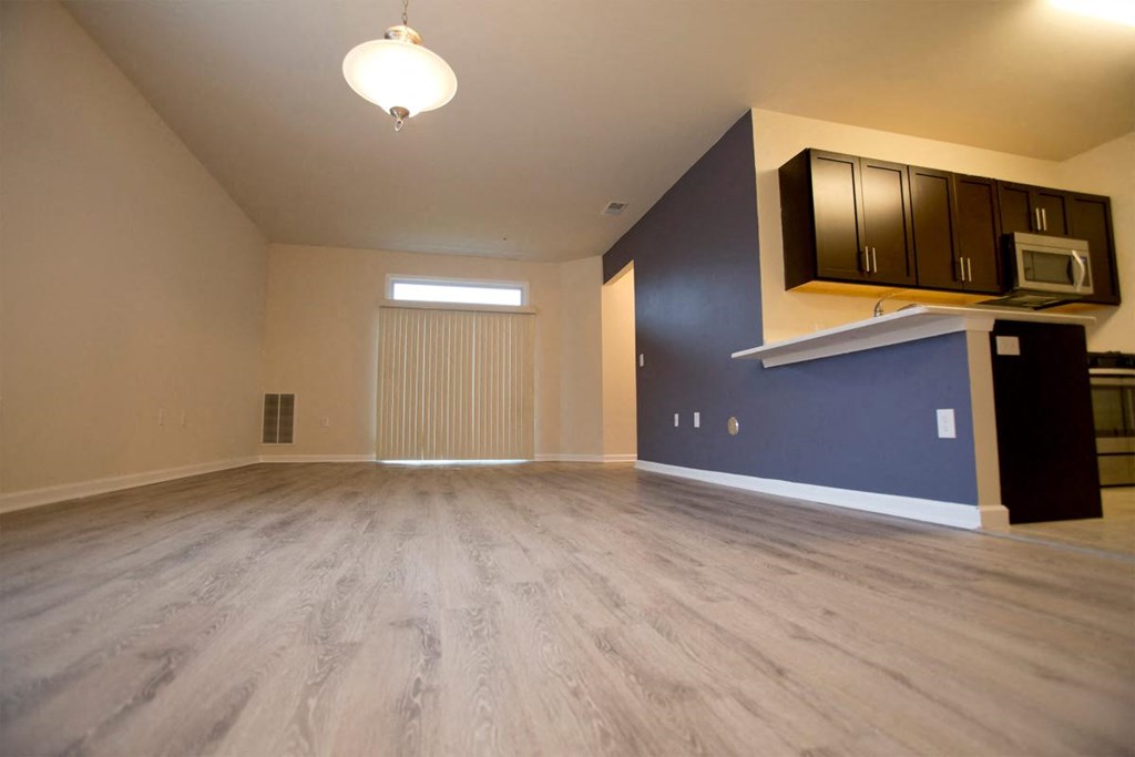 an empty living room with a blue accent wall and wood floors