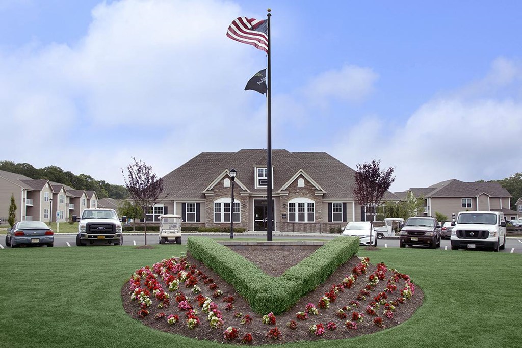 the front yard of a house with an flag and a lawn with cars