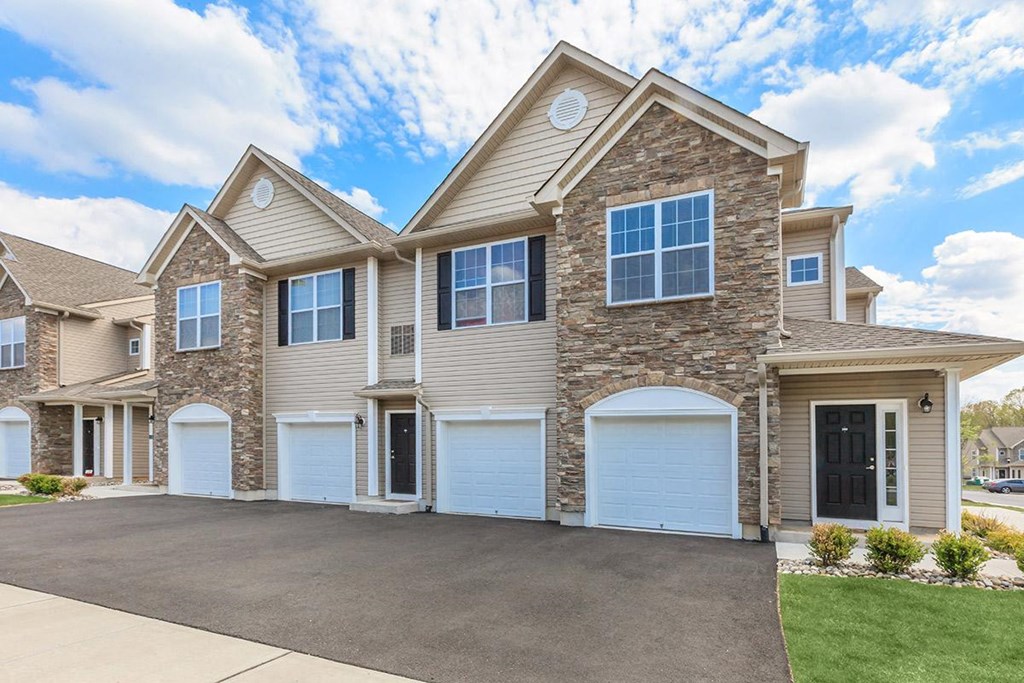a beige and stone house with two garage doors