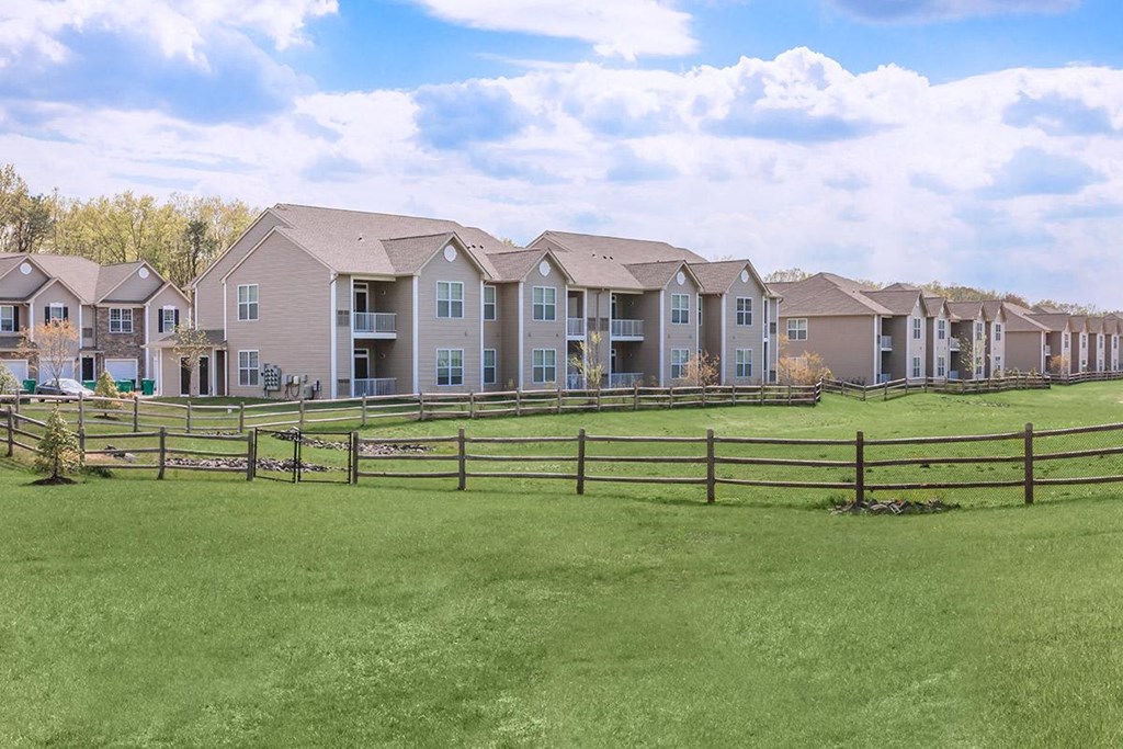 a row of apartment buildings overlooking a green field