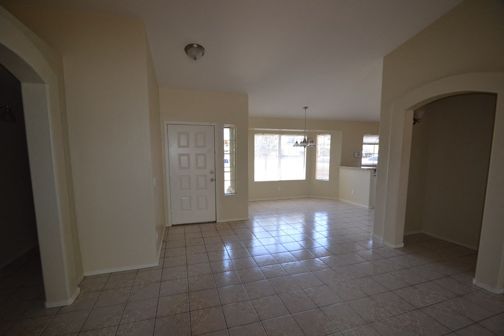 an empty living room with a tile floor and a white door