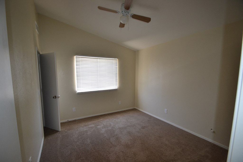 an empty room with a ceiling fan and a window