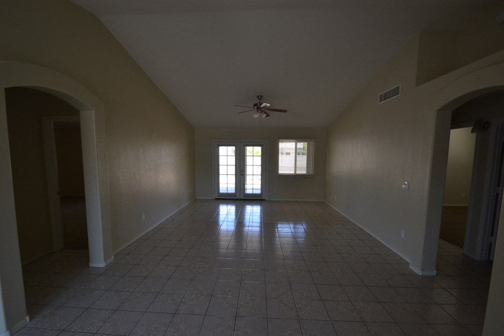 an empty living room with a ceiling fan