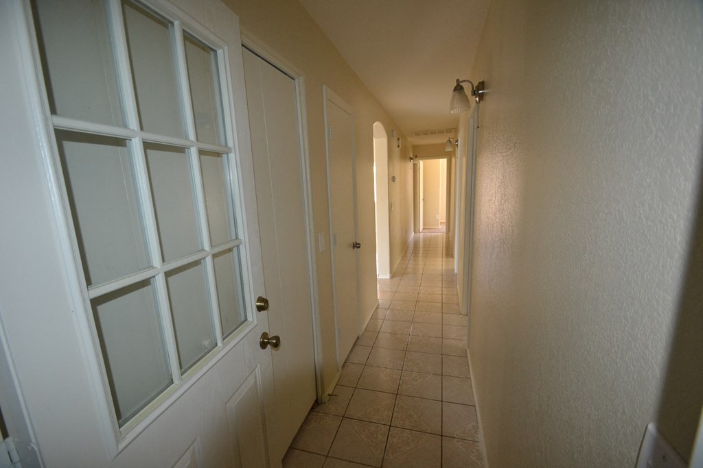a long hallway with white doors and a tiled floor