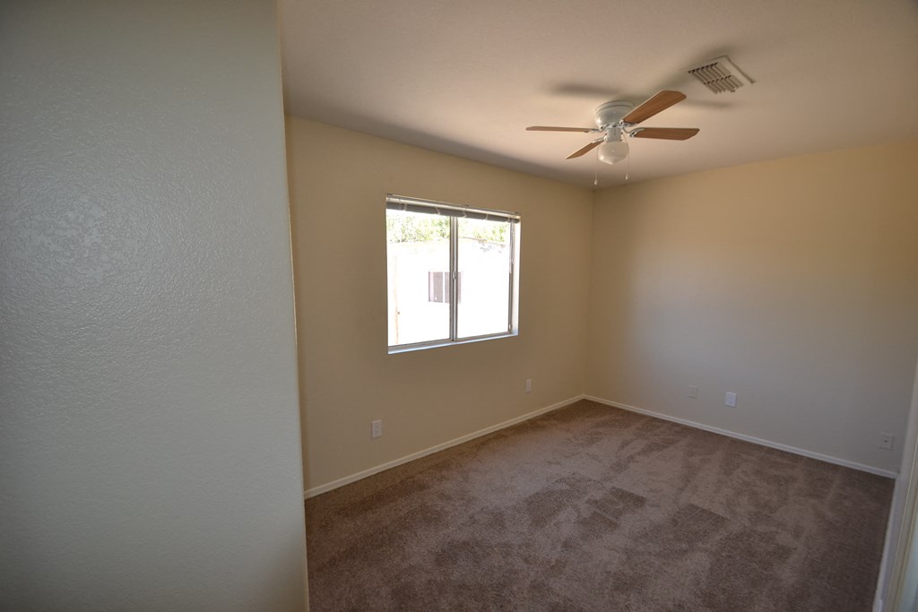 a empty living room with a ceiling fan and a window