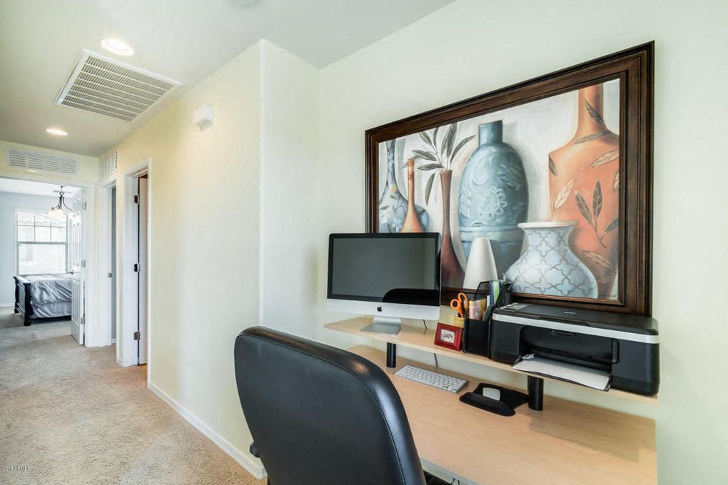 a home office with a computer and a painting on the wall