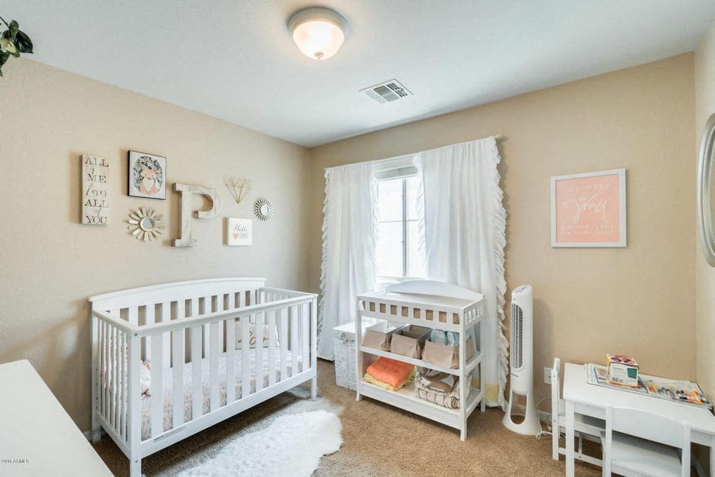 a white nursery with two white cribs and a window