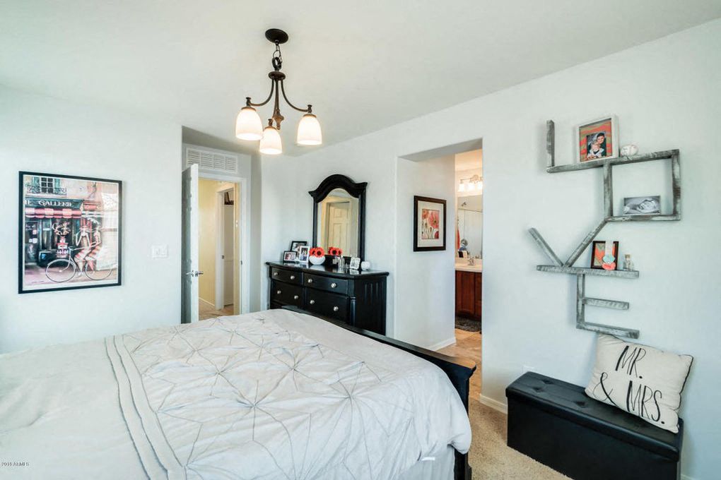 the bedroom has a large bed and a dresser with a mirror