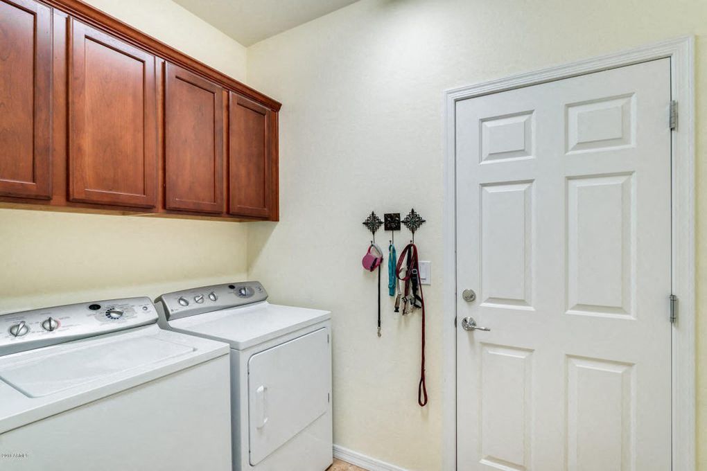 a laundry room with a washer and dryer and wooden cabinets
