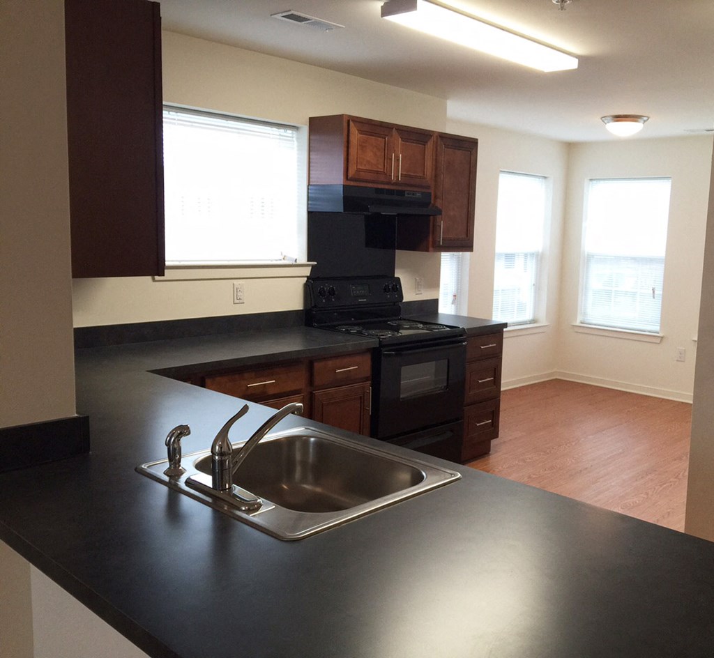an empty kitchen with black counter tops and a sink