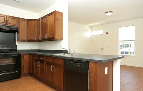 an empty kitchen with wooden cabinets and a black counter top