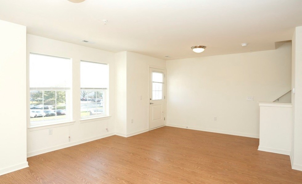 an empty living room with a hard wood floor and three windows