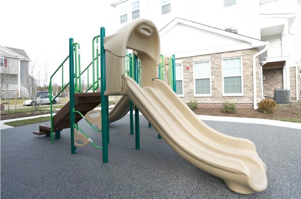 a slide in a playground in front of a house