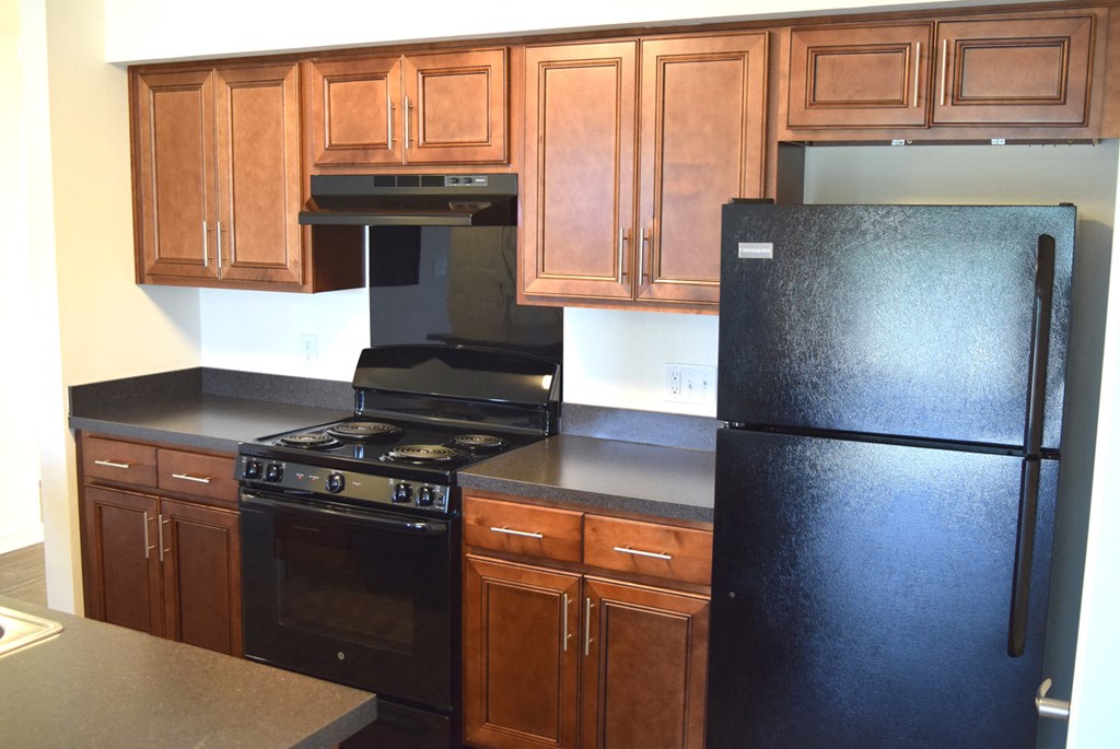 an empty kitchen with black appliances and wooden cabinets