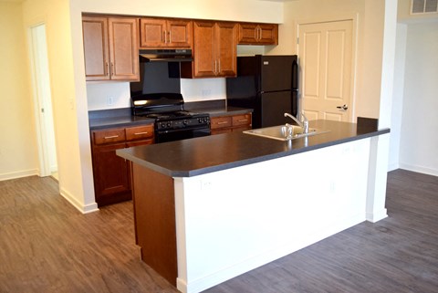 an empty kitchen with wooden cabinets and a black counter top