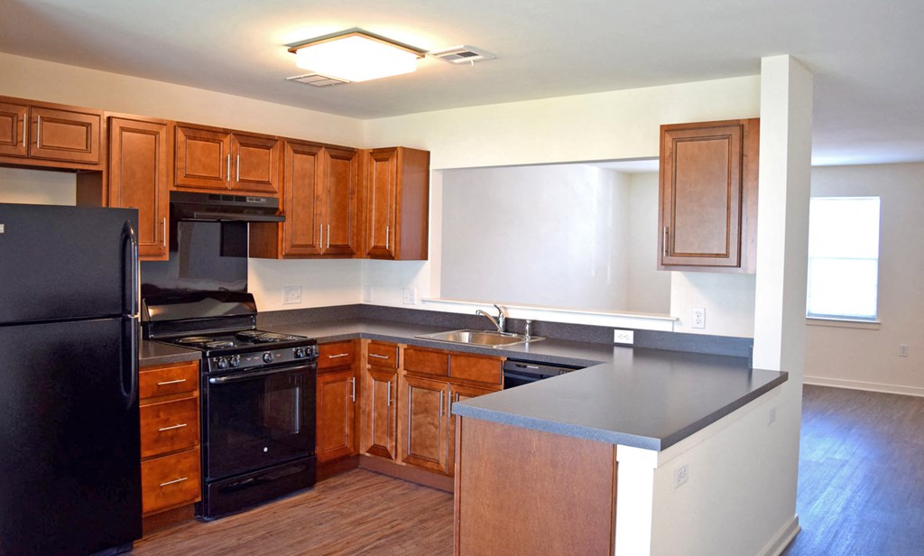 an empty kitchen with black appliances and wooden cabinets