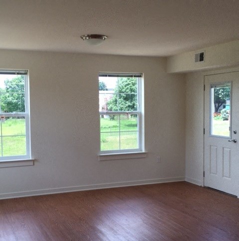 an empty living room with a door and windows